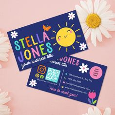 two business cards sitting on top of a pink surface next to flowers and daisies