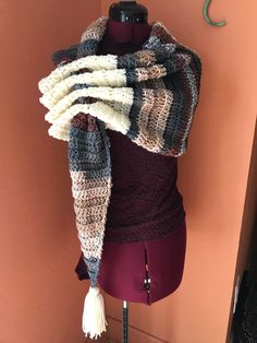 a mannequin wearing a multicolored knitted scarf with tassels