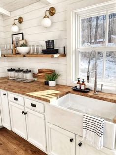 a kitchen with white cabinets and wood counter tops, along with open shelving above the sink