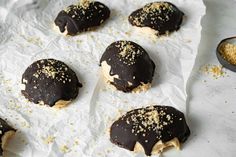 chocolate covered donuts with sprinkles sitting on top of white parchment paper