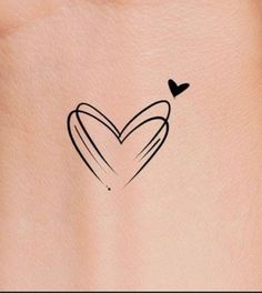 a small heart tattoo on the back of a woman's left side ribcage