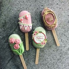 three decorated lollipops sitting on top of a stone floor next to each other