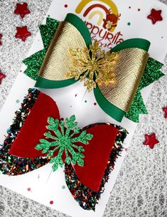 two christmas bows on top of a card with confetti sprinkles