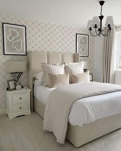 a white bed sitting in a bedroom next to a window with pictures on the wall