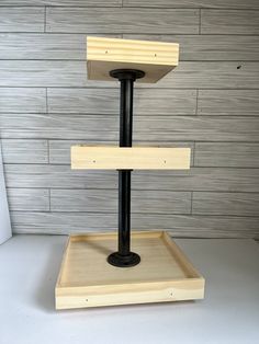 a three tiered wooden stand with black metal base