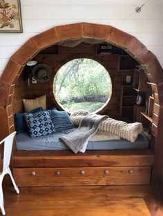 a room with a bed, window and shelves on the wall next to a chair