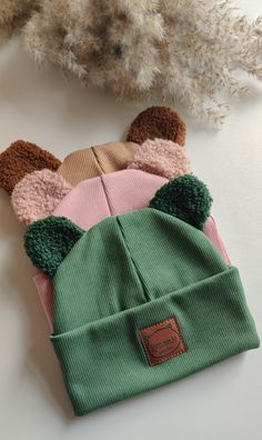 four knitted hats with ears on them sitting next to a feathery planter