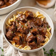 a white bowl filled with beef and noodles