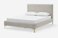 an upholstered bed frame with white pillows