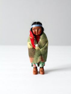 a doll is wearing a green coat and red scarf