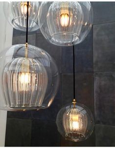 three clear glass globe lights hanging from a ceiling