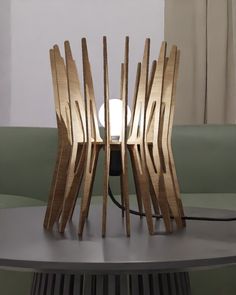 a table lamp made out of wood sticks on top of a round table with a white light