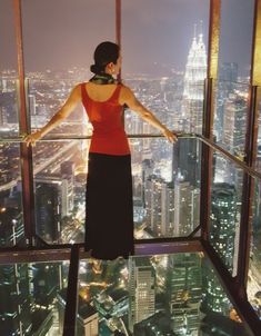 a woman standing on top of a tall building looking out at the cityscape