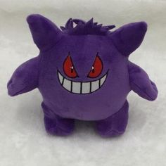 a purple stuffed animal with red eyes and fangs on it's face, sitting in the snow