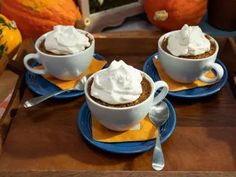 three cups filled with whipped cream on top of blue plates