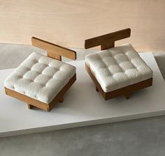 two small wooden stools sitting on top of a white table next to each other