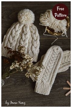 a knitted hat and mittens sitting on top of a wooden table next to knitting needles