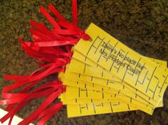 four pieces of yellow paper with red ribbon on them sitting on the ground next to a ruler