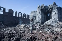 a woman standing in front of a destroyed building