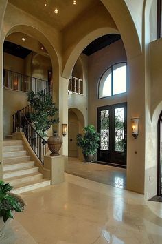 a large foyer with stairs and potted plants