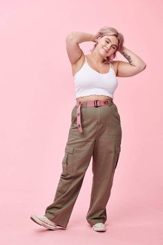 a woman in white shirt and khaki pants posing for the camera with her hand on her head