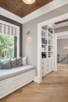 a window seat in the corner of a room with bookshelves and drawers on either side