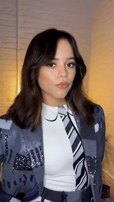 a woman wearing a suit and tie posing for the camera with her hands on her hips