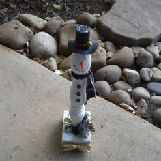 a snowman statue sitting on top of a skateboard in front of some rocks