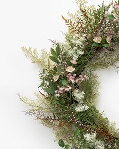 an arrangement of flowers and greenery on a white background