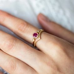 a woman's hand wearing a gold ring with an oval shaped ruby stone on it