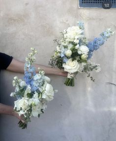 two people holding bouquets of flowers against a wall