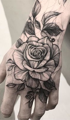 a black and white rose tattoo on the left hand