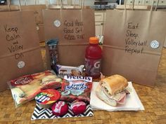 two bags with sandwiches and snacks on them sitting on a table next to each other