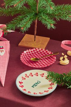 a small christmas tree in a pot next to a plate and other items on a table