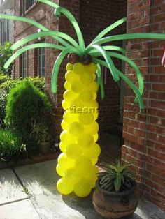 a tall yellow plastic palm tree sitting on top of a sidewalk next to a brick building