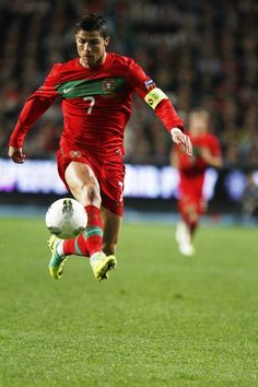 a man kicking a soccer ball on top of a field