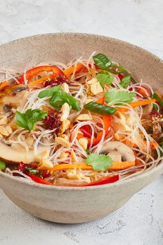 a bowl filled with noodles and vegetables on top of a table