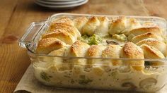 a casserole dish filled with rolls and broccoli on top of a wooden table