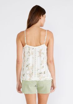 An ultra-pretty lace-trimmed camisole designed in an ivory and pink floral print. Floral print Relaxed fit Sleeveless Hip length V-neckline Ruffle hemline Lace trim Adjustable spaghetti straps Spring floral camisole It doesn't get much cuter than this flowy floral print camisole with delicate lace trim details. Featuring a flirty ruffle hem, this romantic bohemian top can be styled casually with your favorite pair of jeans or dressed up for date nights. Model is 5'9, wearing a size XS.Style: I-1 Feminine Floral Print Spaghetti Strap Camisole, Feminine Delicate Lace Tank Top For Spring, Feminine Lace Trim Spaghetti Strap Camisole, Feminine Lace Trim Camisole With Spaghetti Straps, White V-neck Tank Top With Floral Print, White Floral Print Camisole Tank Top, Feminine Cream Camisole Tank Top, Spring Delicate Lace Tank Top With Spaghetti Straps, Spring Delicate Lace Sleeveless Camisole