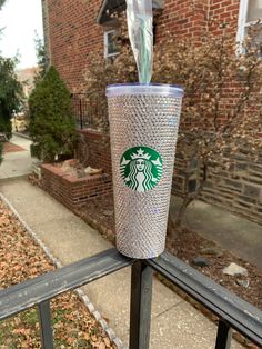 a starbucks cup with a straw sticking out of it sitting on a railing next to a brick building