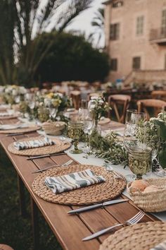 a long table is set up with place settings and flowers on it for an outdoor dinner