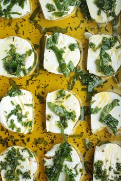 several pieces of bread with cheese and greens on them sitting on a yellow surface,