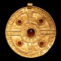 an old gold pendant with red stones on it