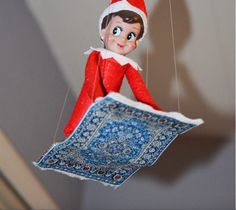 an elf hanging from a string with a rug underneath it