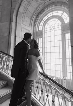 a man and woman are kissing on the stairs in an old building with arched windows