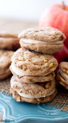 a stack of cookies sitting on top of a blue plate next to an orange apple