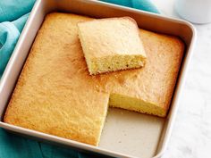 a pan filled with cake next to a cup of coffee on top of a blue towel