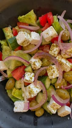 a salad with tomatoes, cucumbers, onions and feta cheese in a bowl