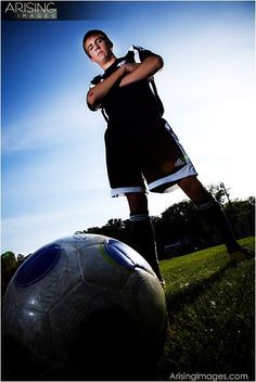 a young man standing next to a soccer ball