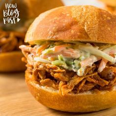 a pulled pork sandwich with coleslaw and slaw on a wooden table top